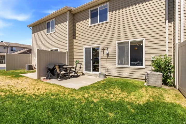 Private patio area with concrete hardscaping, partial privacy fencing, and direct access to interior via sliding glass door