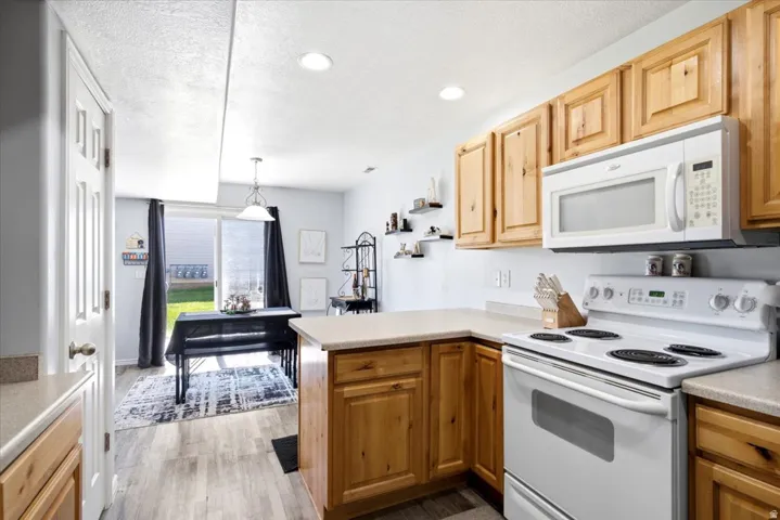 Light wood-finish cabinetry with white appliances, including a range and over-the-range microwave