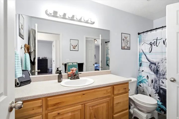 Vanity with wood-finish cabinetry, integrated sink, and light-toned countertop