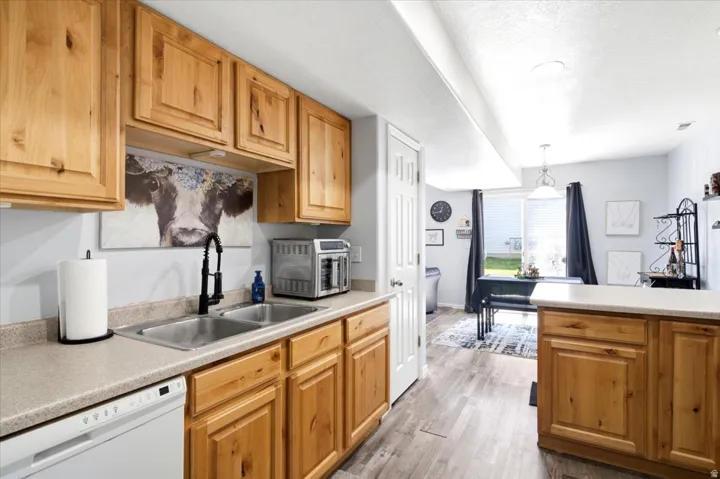 Kitchen featuring wood-finish cabinetry, a double basin stainless steel sink with a matte black faucet, and light-toned countertops