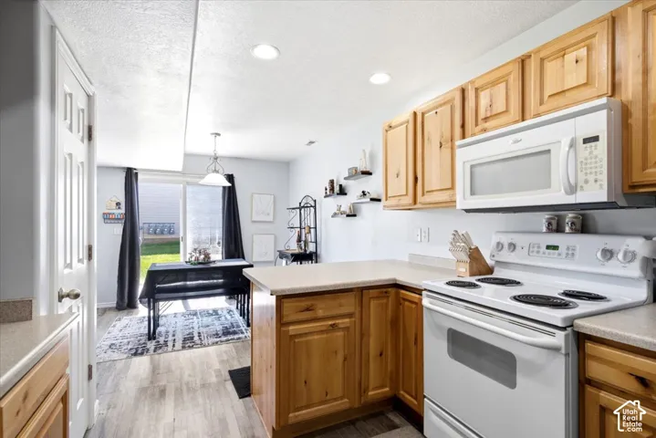 Light wood-finish cabinetry with white appliances, including a range and over-the-range microwave