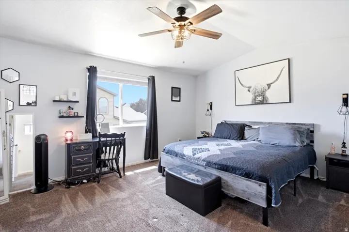 Vaulted ceiling with a ceiling fan, carpeted flooring, a window with a sill, and built-in wall shelving