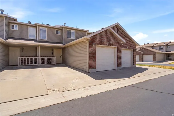 Brick and siding exterior with two garage doors and an attached covered porch