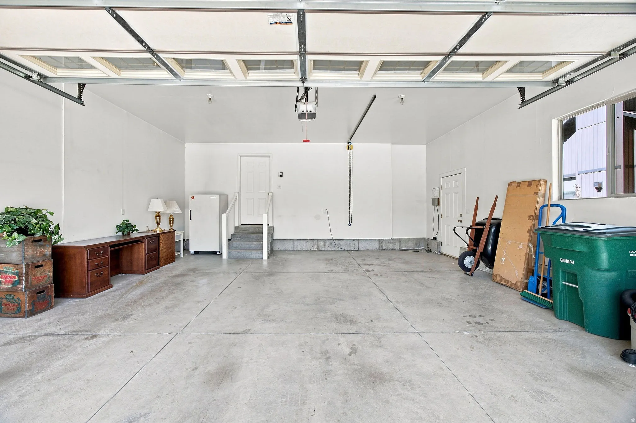 Large garage space with a concrete floor, overhead lighting, and an automatic garage door opener