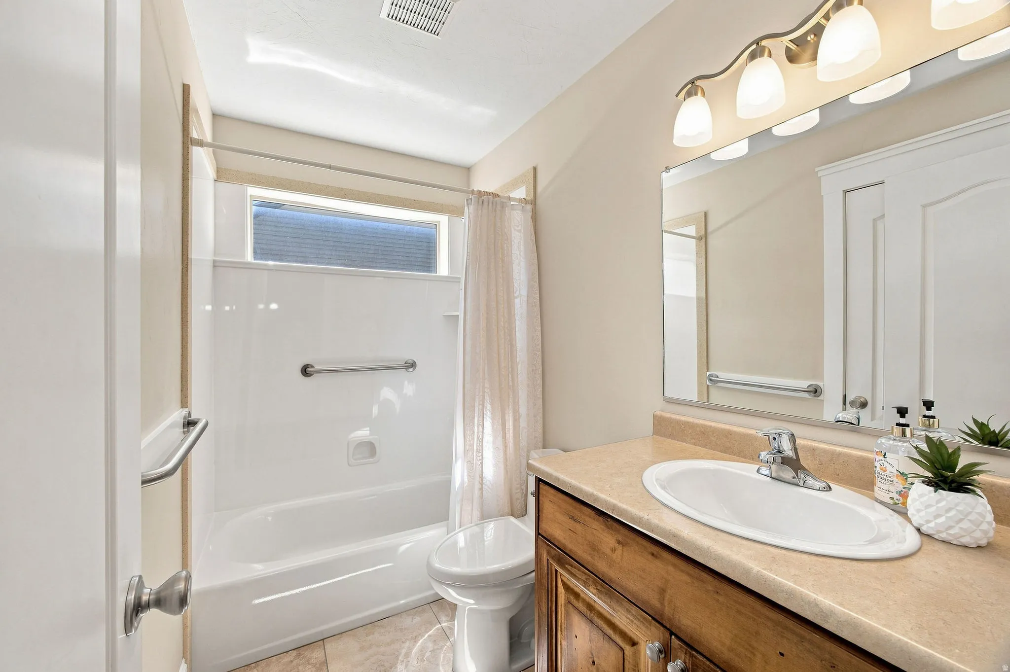 Full main bathroom featuring a single vanity with wood cabinetry, a built-in sink, a large mirror, and a tub with an overhead shower