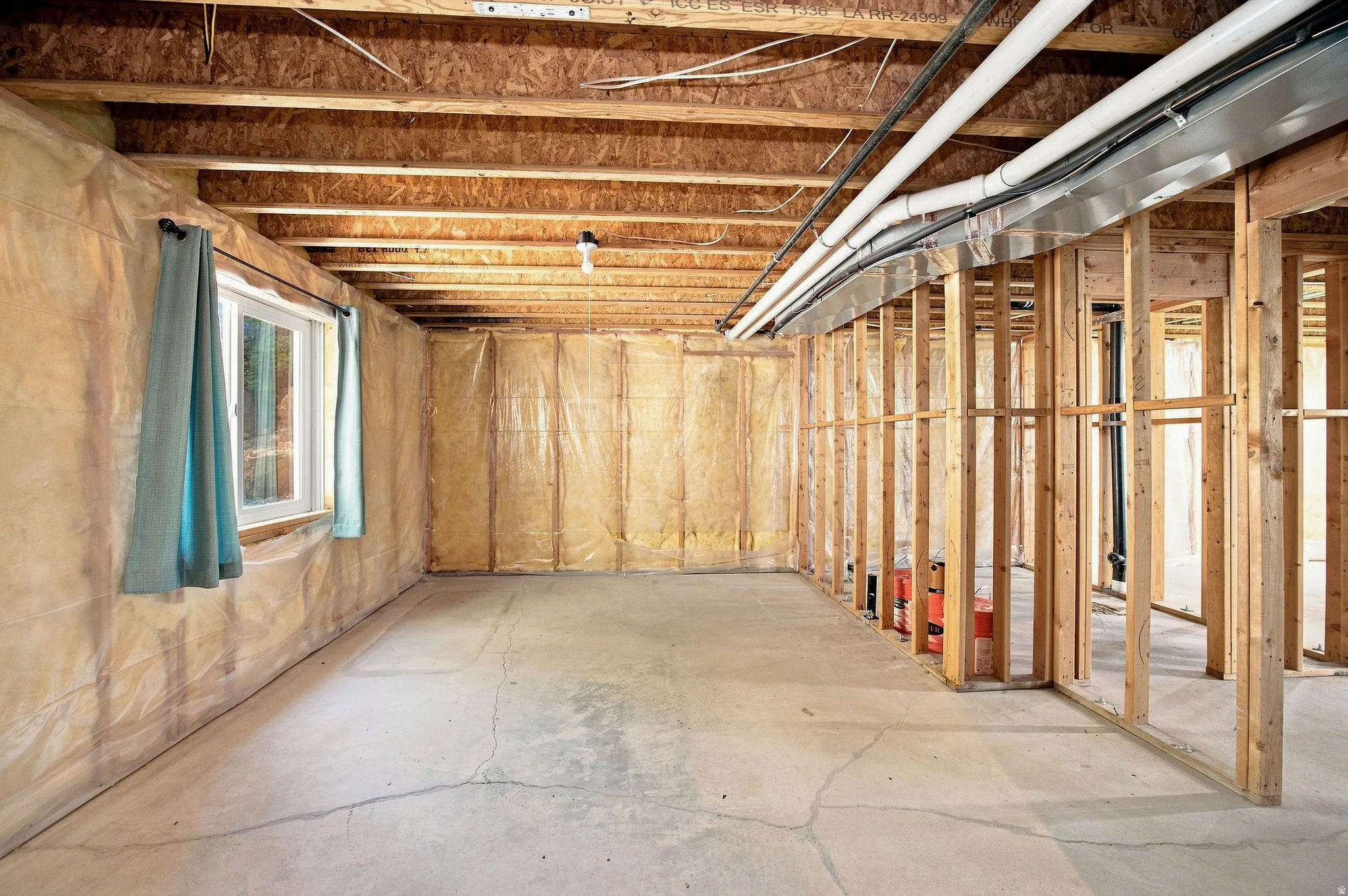 Unfinished basement. Concrete flooring, exposed wood framing, ceiling joists, and a single window