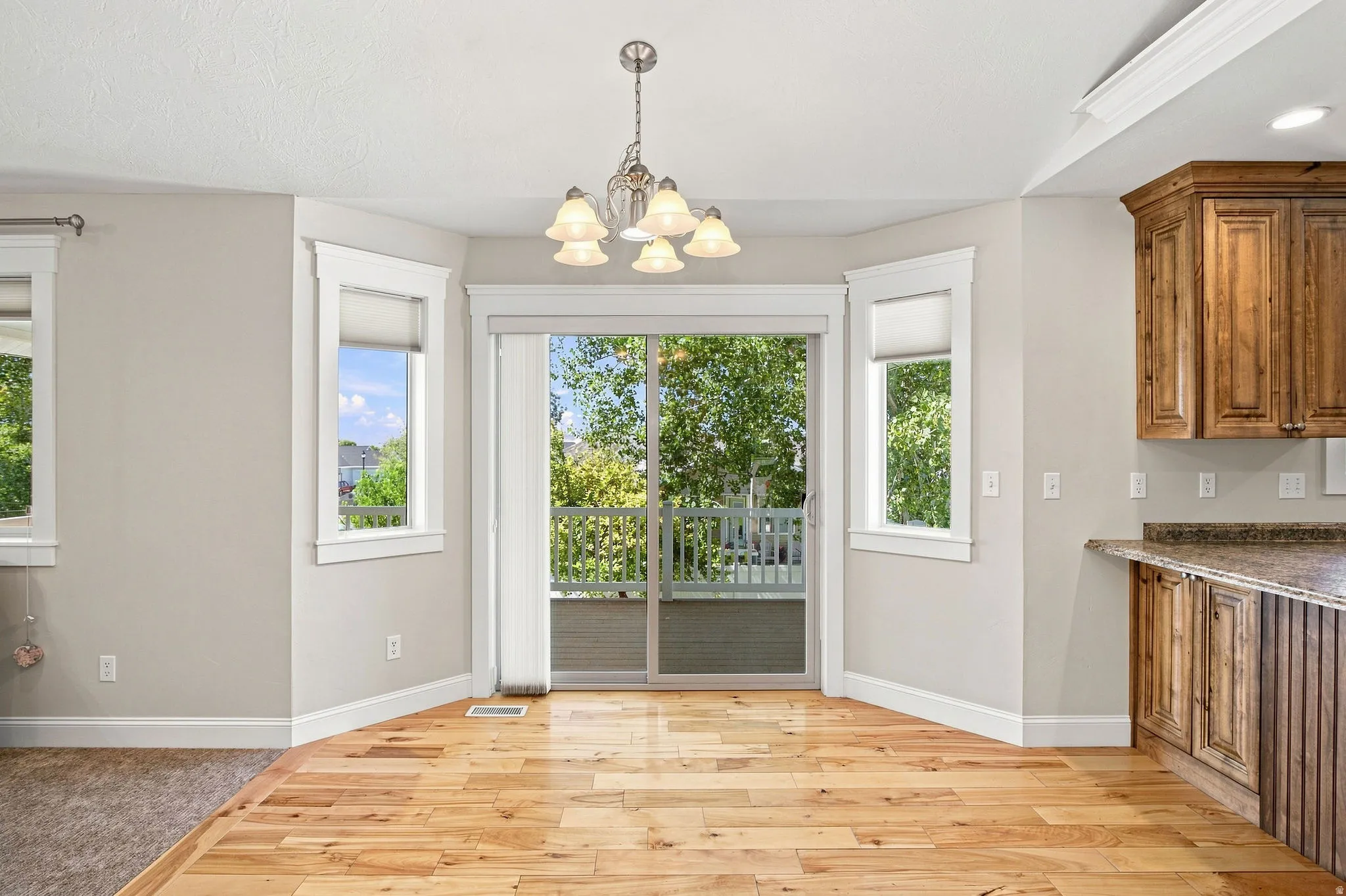 Hardwood flooring, sliding glass door, multiple windows with white trim, built-in cabinetry, and a pendant light fixture