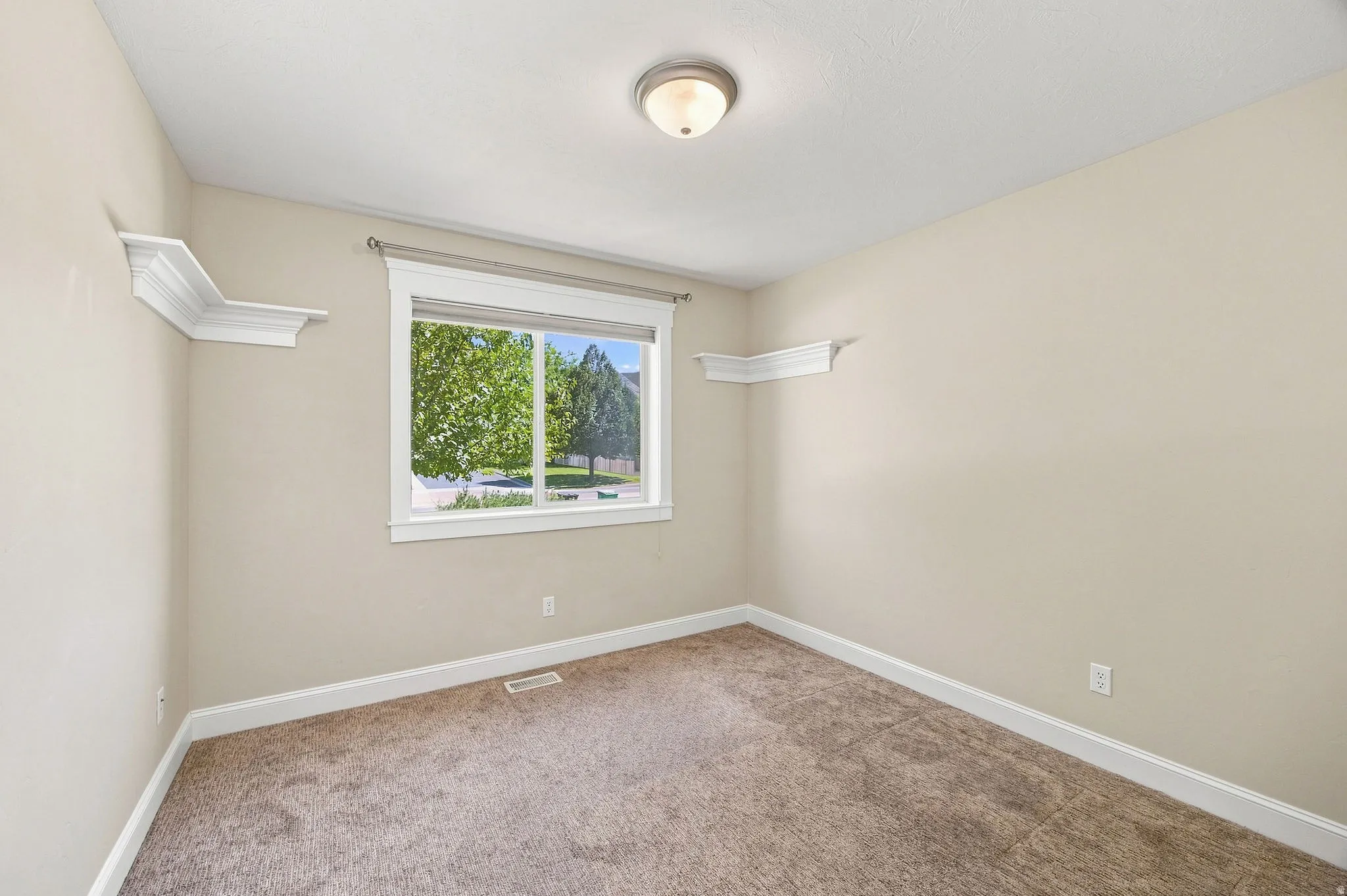 Bedroom 2. Neutral wall finishes, carpeted flooring, window with white trim, and a ceiling-mounted light fixture