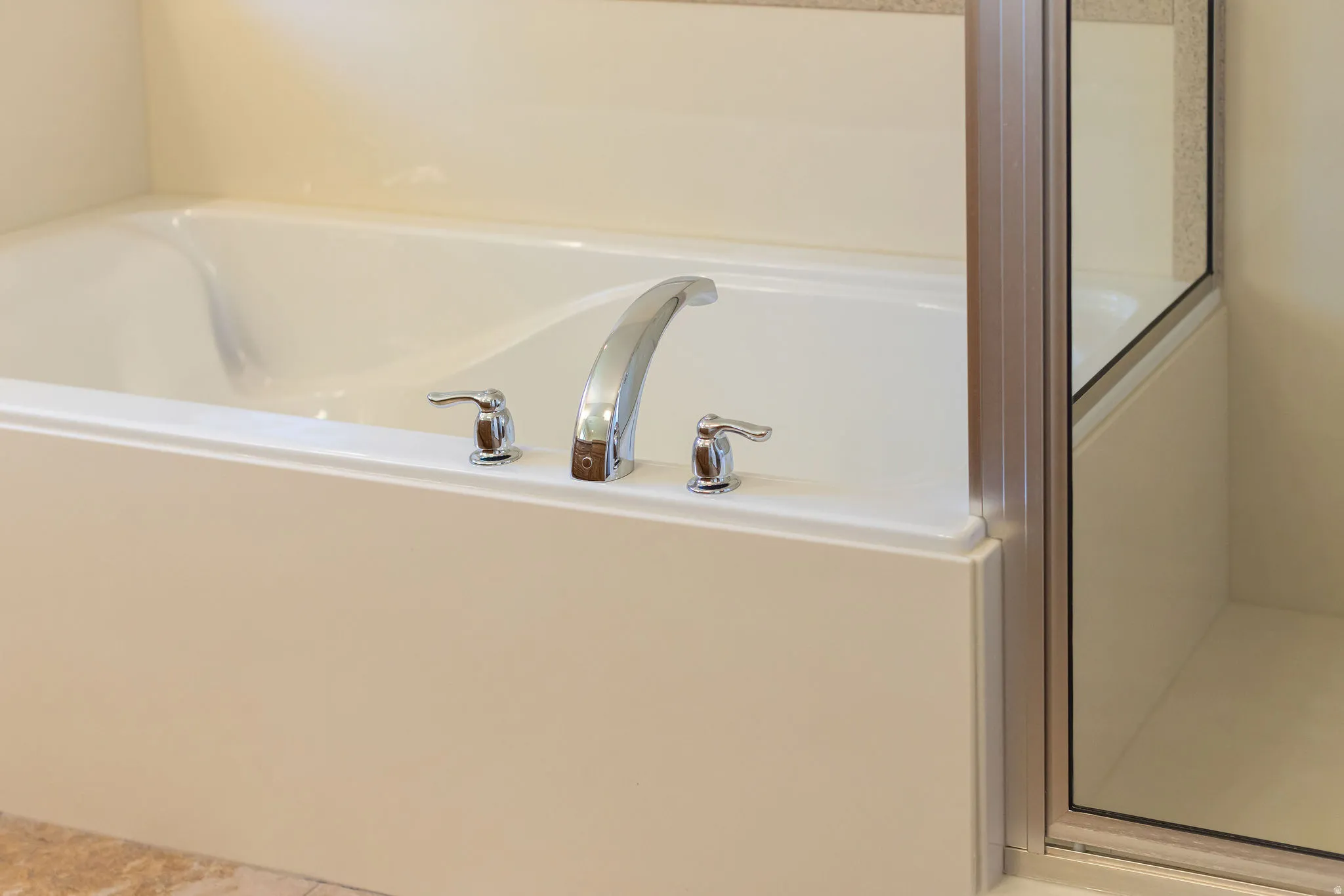 Primary ensuite. Integrated bathtub with chrome fixtures and adjacent glass-enclosed shower