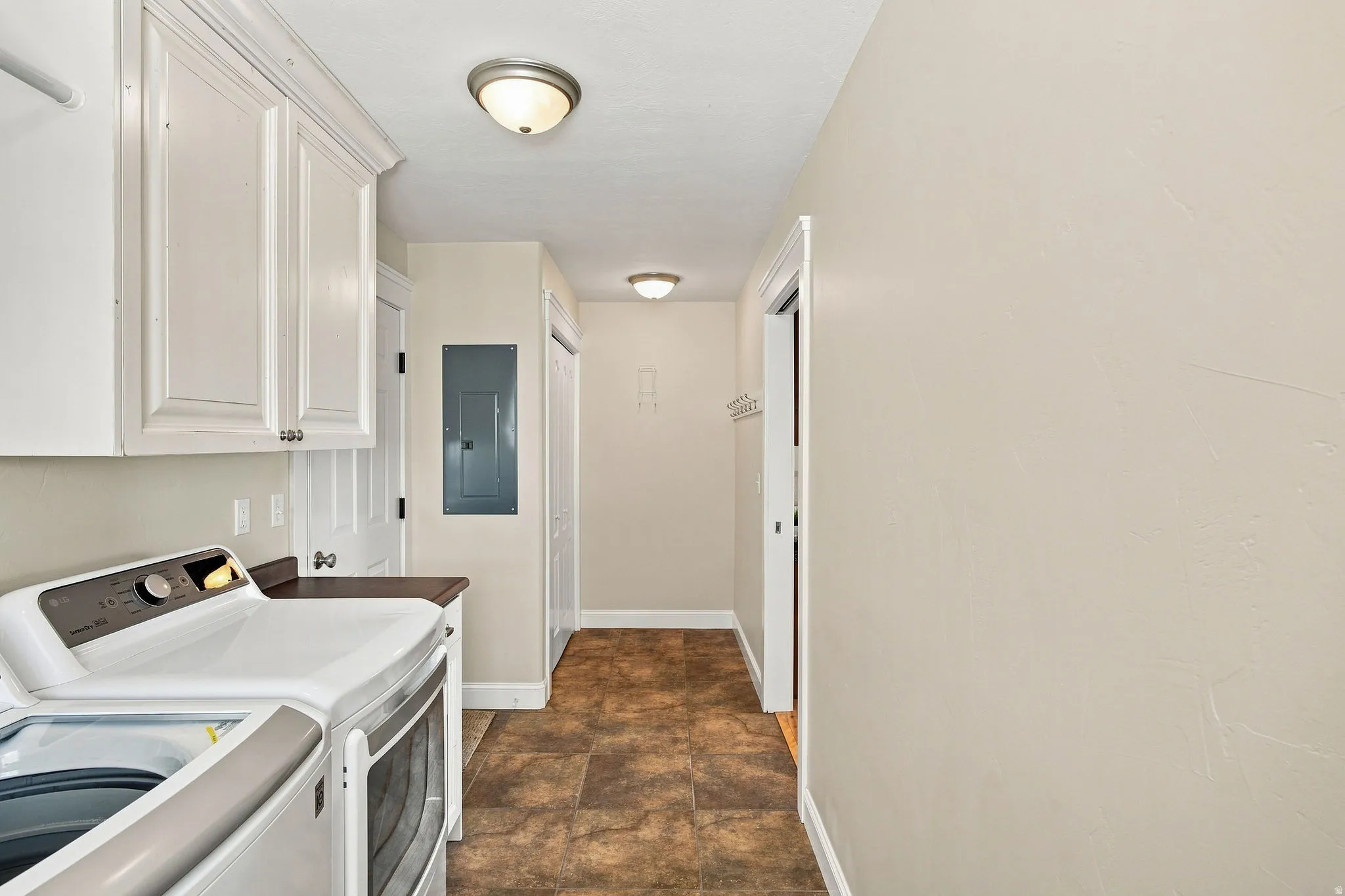 White cabinetry with crown molding, solid surface countertop, tiled flooring, and flush mount lighting