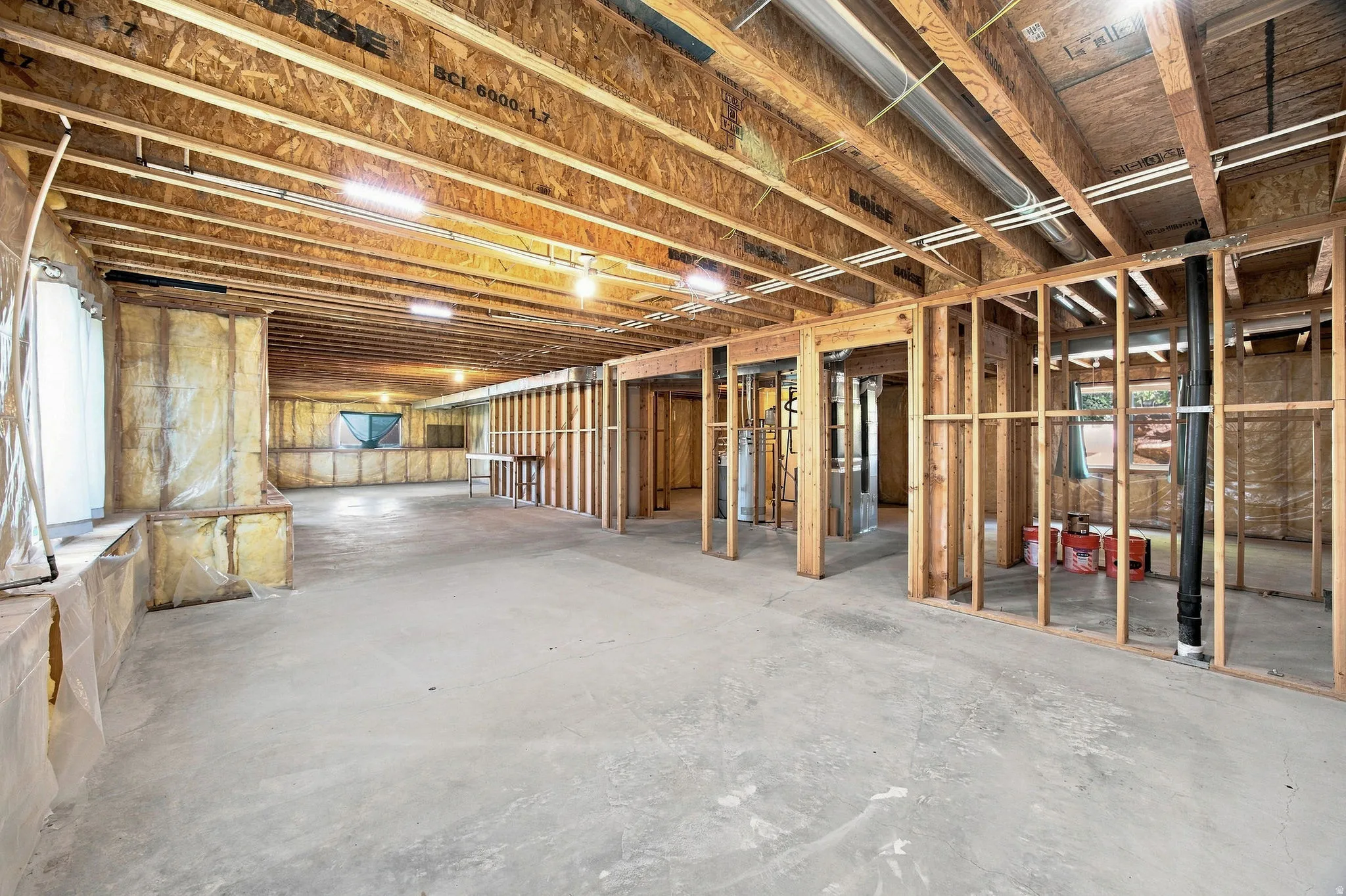 Unfinished basement featuring exposed wood framing, concrete flooring, and ample open space