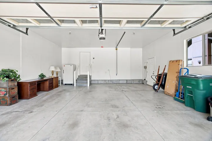 Large garage space with a concrete floor, overhead lighting, and an automatic garage door opener