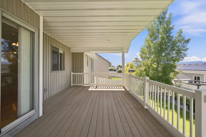 Covered deck featuring composite decking, white railing, and sliding glass door access