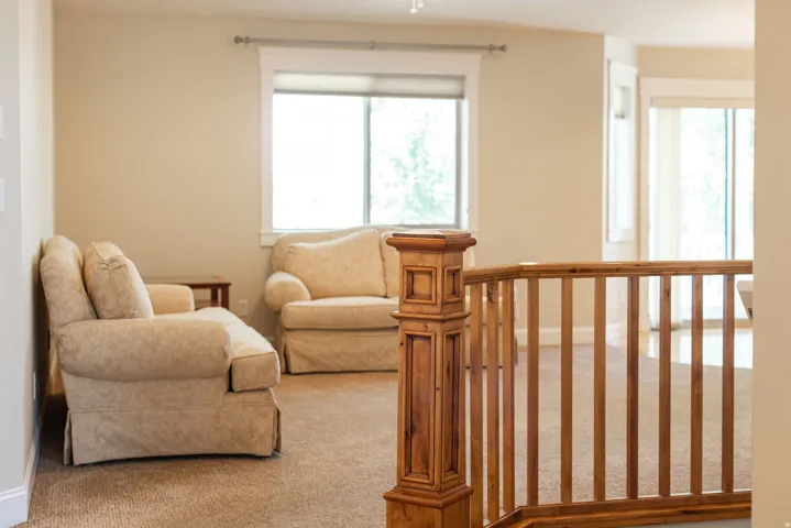 Carpeted flooring with a wood railing and newel post