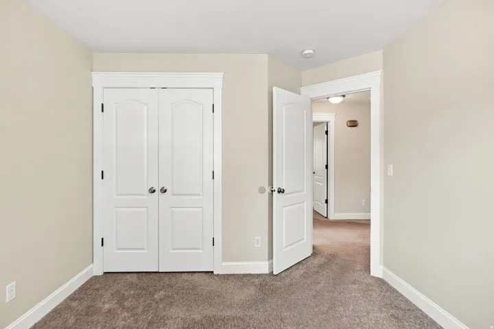 Bedroom 2. Neutral tone walls with white trim, two-panel interior doors, and plush carpeting