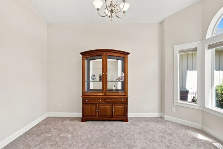 Arched window with upper transom, multiple pane windows, and a chandelier lighting fixture. Bay windows and carpeted floors.
