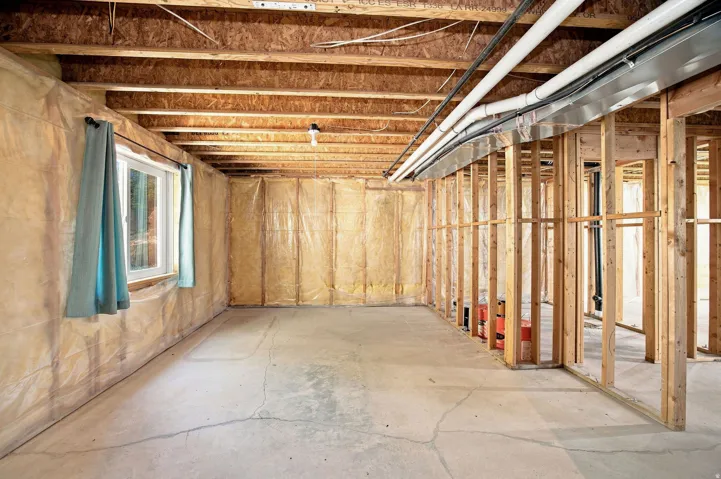 Unfinished basement. Concrete flooring, exposed wood framing, ceiling joists, and a single window