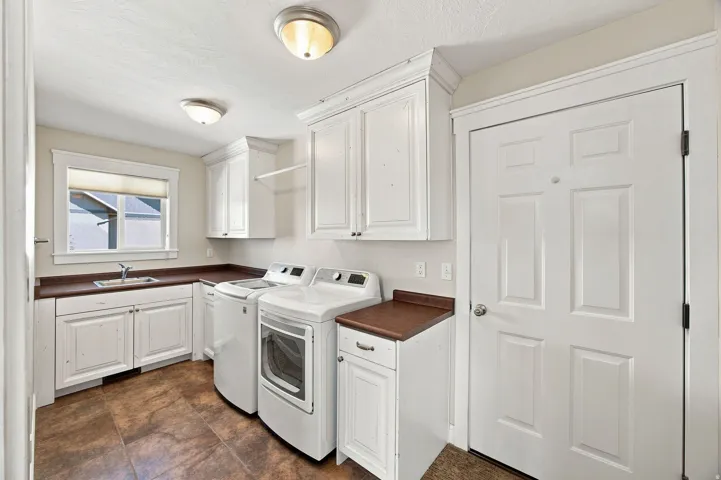 White cabinetry with crown molding, integrated sink, wood-finish countertops, and durable tile flooring