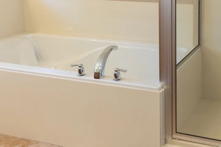 Primary ensuite. Integrated bathtub with chrome fixtures and adjacent glass-enclosed shower