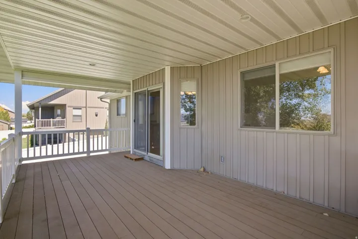 Covered outdoor deck with composite decking, white railing, and sliding glass door access