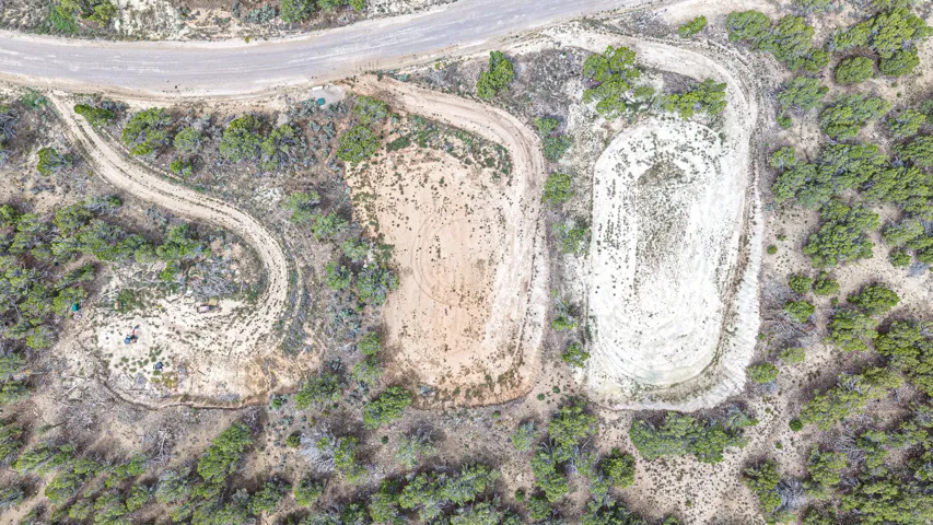 Expansive undeveloped land featuring a cleared building site, natural terrain, and established road access