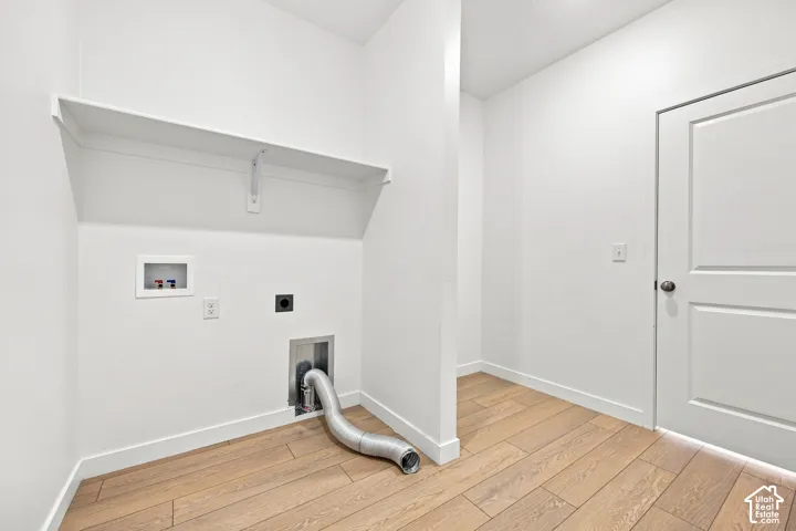 Dedicated laundry area featuring a built-in shelf, appliance hookups, and wood-finish flooring