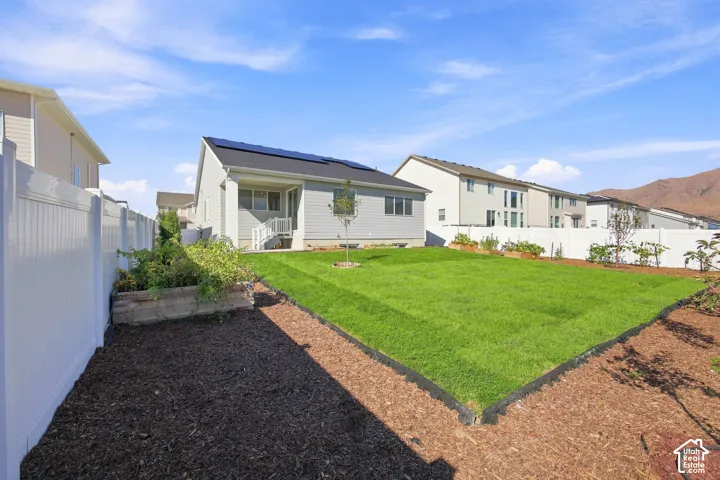 Expansive backyard featuring a manicured lawn, established garden beds, and privacy fencing