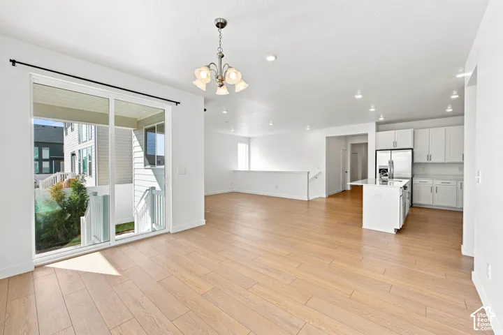 Open-concept layout with wood-finish flooring, white cabinetry, and stainless steel appliances