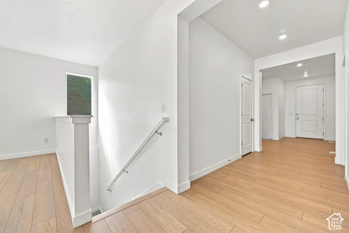 Wood-finish flooring, recessed lighting, white interior doors, and a window providing ambient light