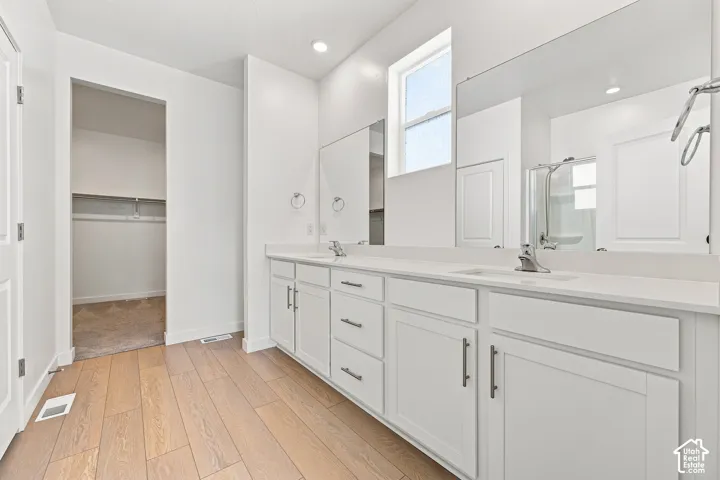 Master bathroom: Dual vanity with white cabinetry, integrated sinks, chrome fixtures, and a large wall mirror