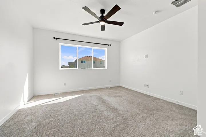 Master bedroom: Neutral tone wall paint, light gray carpet flooring, ceiling-mounted fan fixture, and a large window