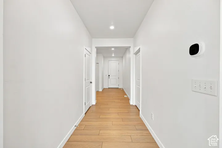 Hallway featuring wood-finish flooring, white walls, recessed lighting, and white interior doors