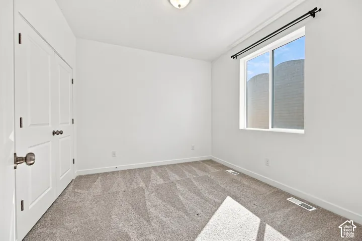 Bedroom 2: White walls, light gray patterned carpeting, white window trim, and a ceiling-mounted light fixture