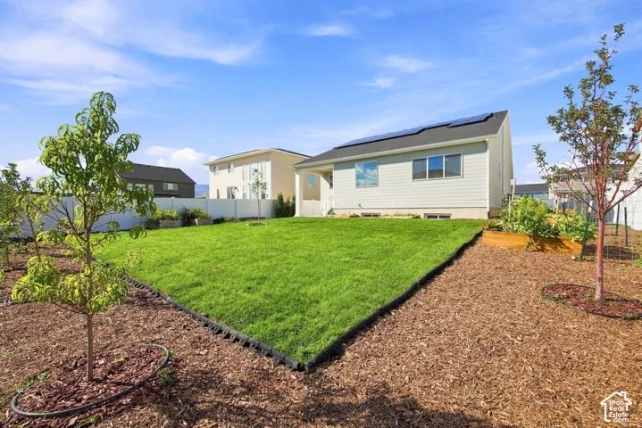 Expansive backyard featuring a manicured lawn, established trees, and a raised garden bed