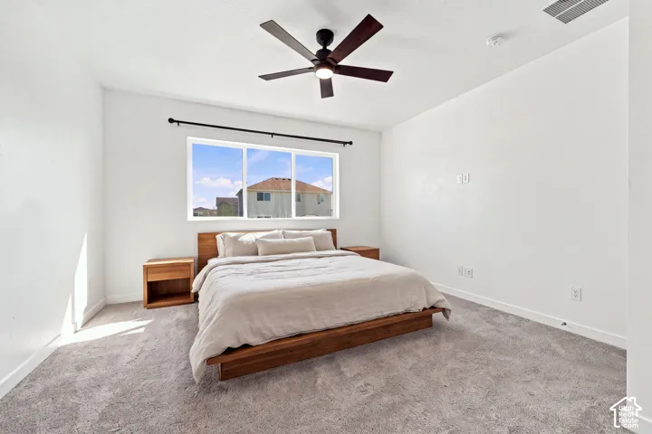 Master bedroom: Recessed window with a black curtain rod, light gray carpet flooring, and a ceiling fan with dark wood-finish blades