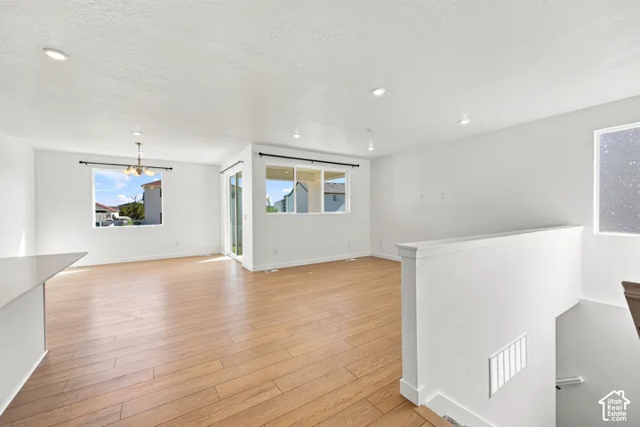 Recessed lighting throughout, wood-finish flooring, white painted walls, sliding glass door, and a built-in light fixture