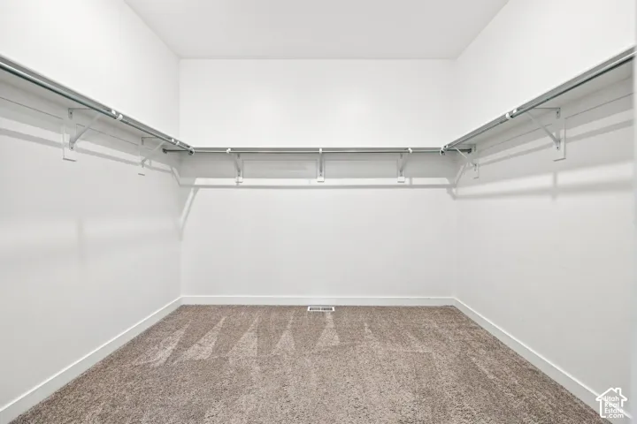 Master bedroom: Expansive walk-in closet with carpeted flooring
