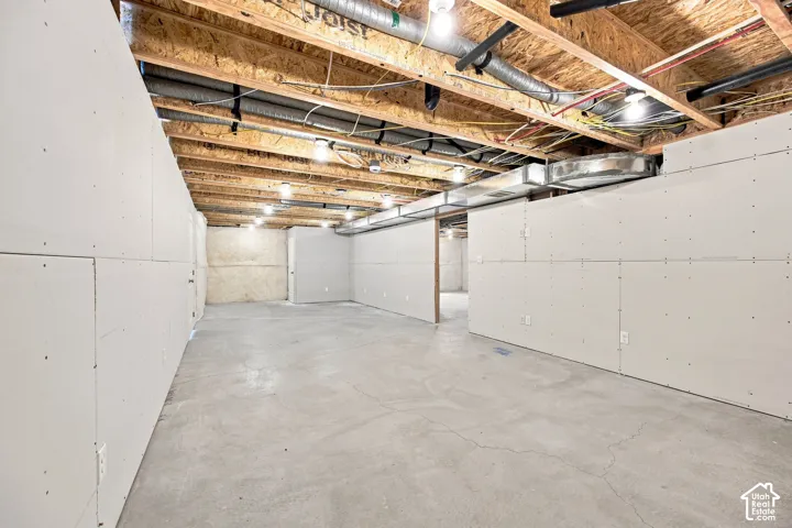 Unfinished lower level with concrete flooring, framed walls, and exposed ceiling joists