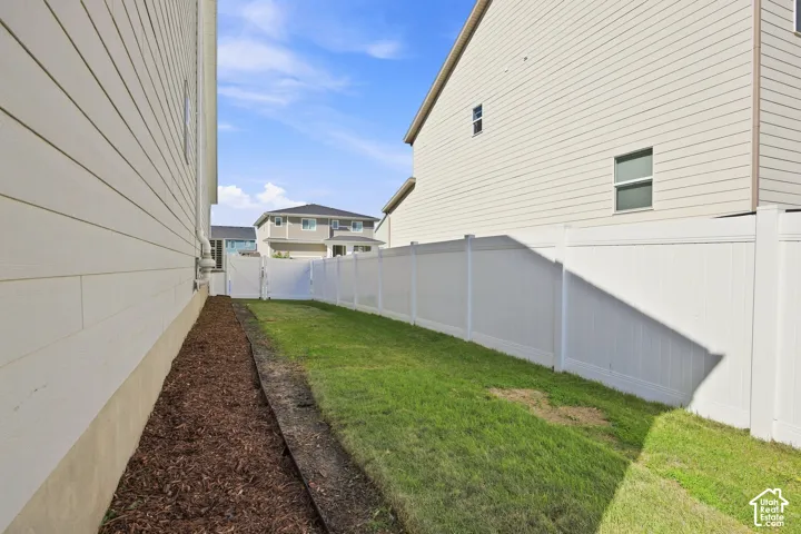 Fully fenced backyard featuring a white vinyl fence and a lawn area