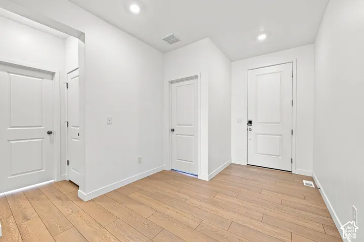 Wood-finish flooring throughout, bright white walls, recessed ceiling lighting, and panel interior doors