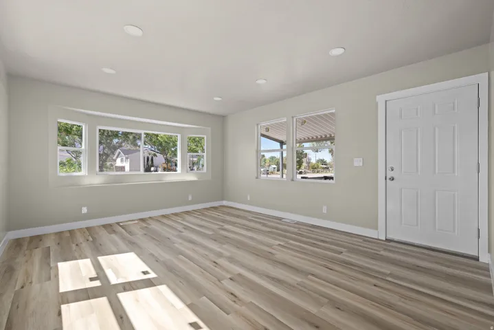 Recessed lighting, wood-finish flooring, bay window, white paneled door, and neutral wall tones