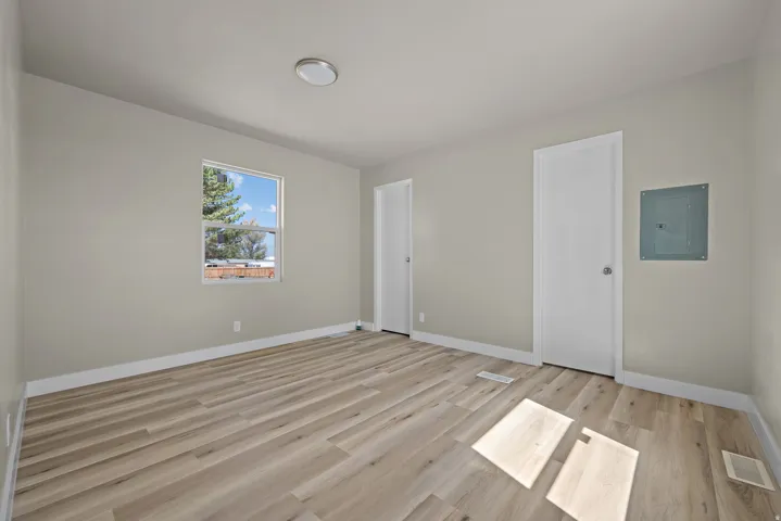 Neutral wall paint, wood-finish flooring, white trim, single window, and a flush-mount ceiling light fixture