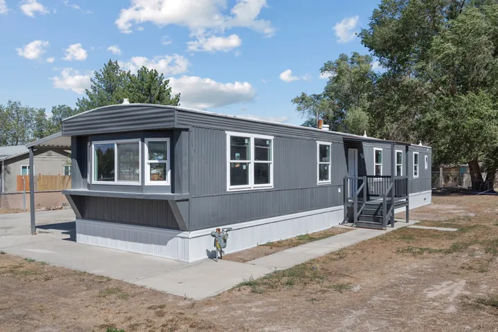 Gray exterior siding, white window trim, covered entry, front porch with railing, concrete walkway