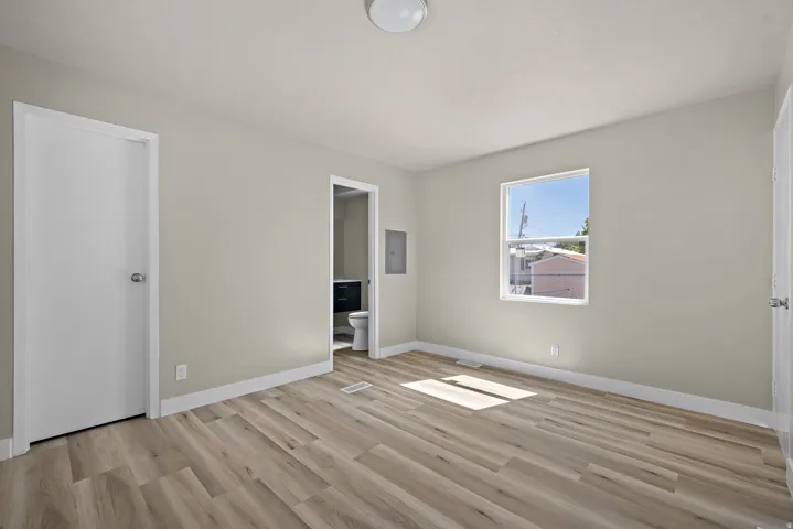 Wood-finish flooring, neutral wall paint, white trim, and a window with a white frame