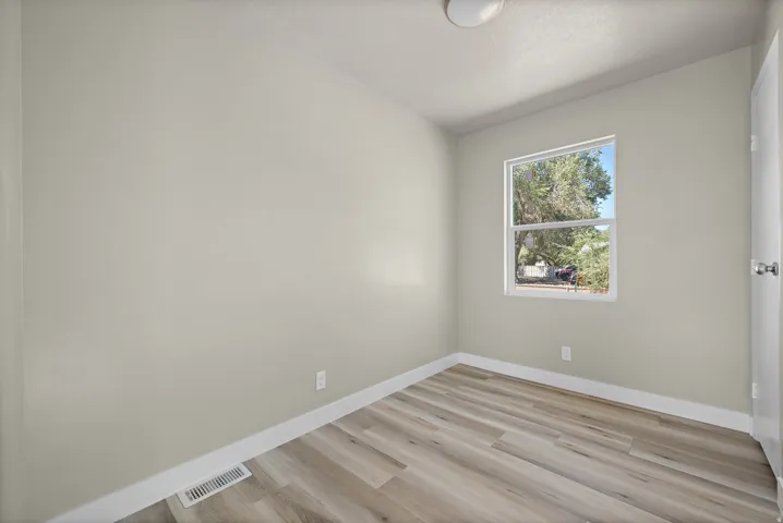 Warm neutral wall tones, wood-finish flooring, and a window with natural light