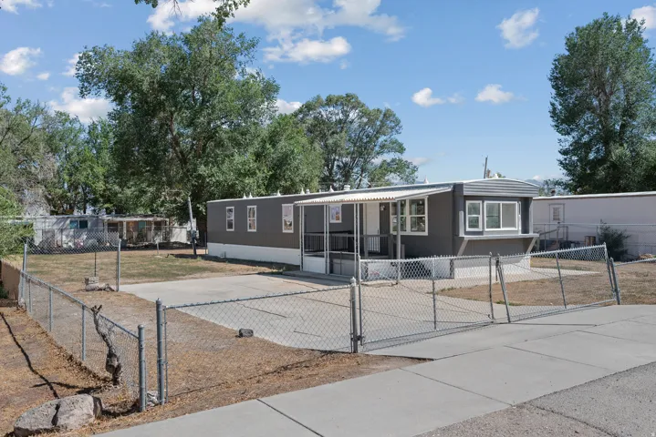 Gray exterior siding with white trim, covered front porch, fenced yard with chain-link fencing, paved driveway