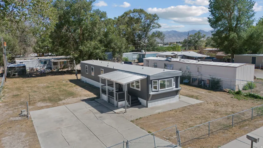 Gray-sided manufactured home featuring a covered front porch, bay window, and a concrete driveway