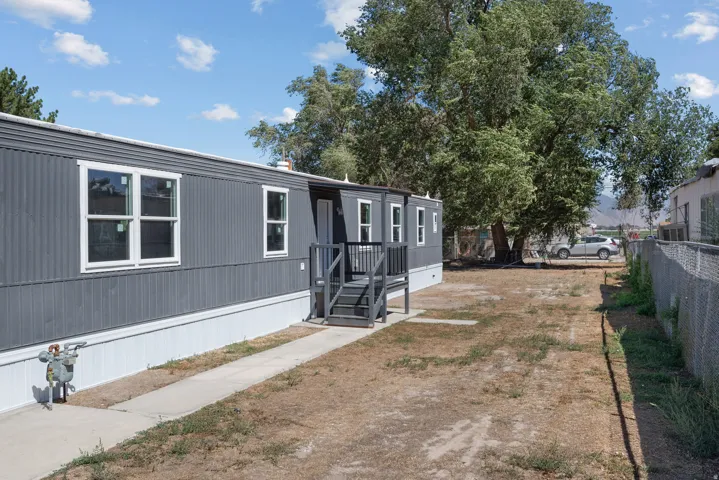 Exterior featuring dark gray siding, white window trim, a dark gray entry deck, and a concrete walkway