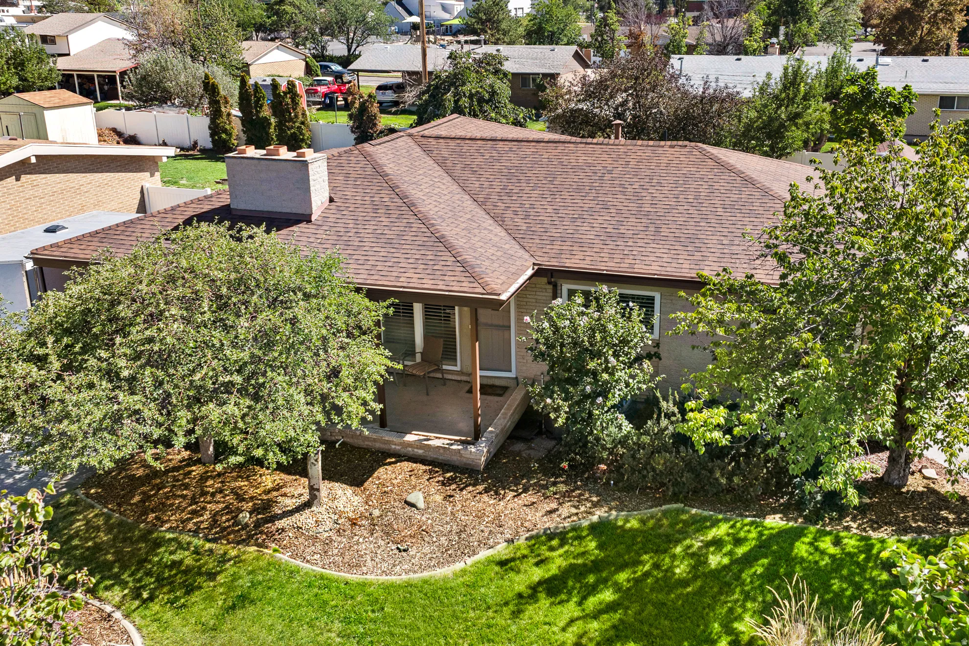 Pitched roof, brick chimney, covered porch, mature trees, manicured lawn