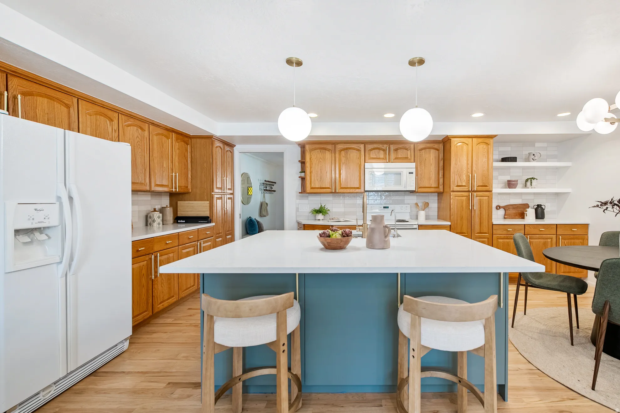 Kitchen featuring wood cabinetry, white appliances, a center island with a white countertop, and wood-finish flooring